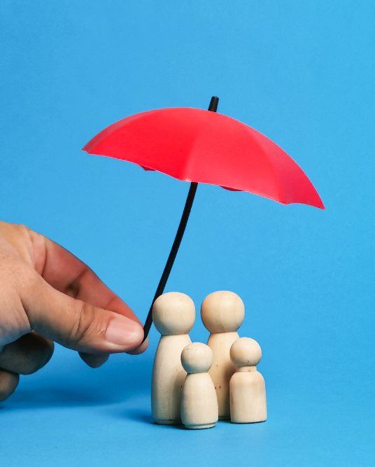 hand holding umbrella over wooden family statues
